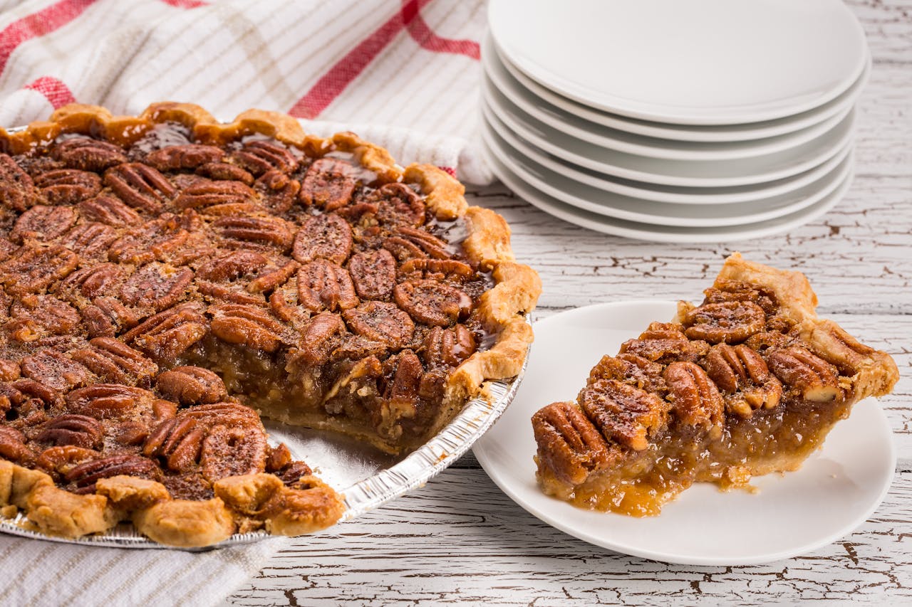 Mouthwatering pecan pie with a slice served on a white plate. Perfect for desserts or southern cuisine enthusiasts.