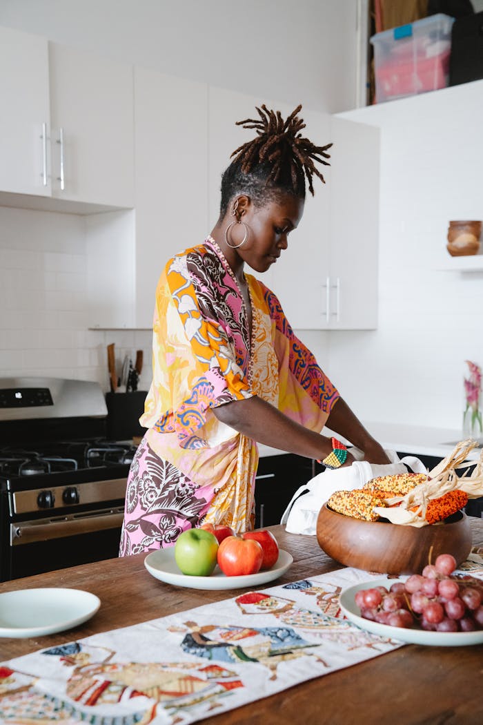 African American woman arranging fruit and grains in a modern kitchen setting, vibrant atmosphere.